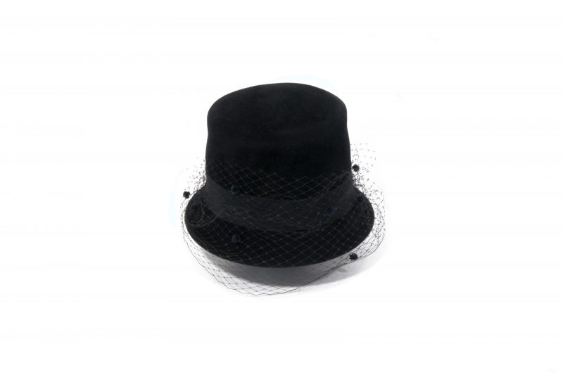 De hoge hoed van het Maison Fabienne Delvigne is resoluut modern en is versierd met een grofkorrelig lint en een bijpassende gevlekte sluier.